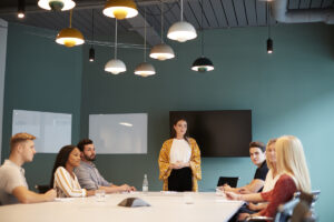 Businesswoman Addressing Group Of Candidates Meeting Around Table At Graduate Recruitment Assessment Day #image_title